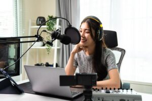 woman podcasting on a computer talking to a podcasting microphone